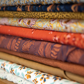 Warm coloured printed fabrics stacked on top of each pther